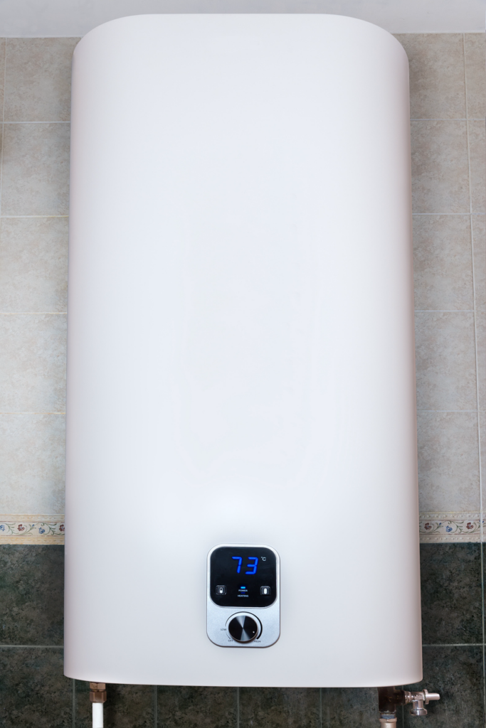 A white-colored tankless electric water heater hanging on a wall.
