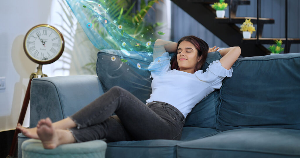 Happy gen z beautiful smiling woman sitting rest sofa raising arms stretching back muscles enjoy feel peaceful weekend at home.